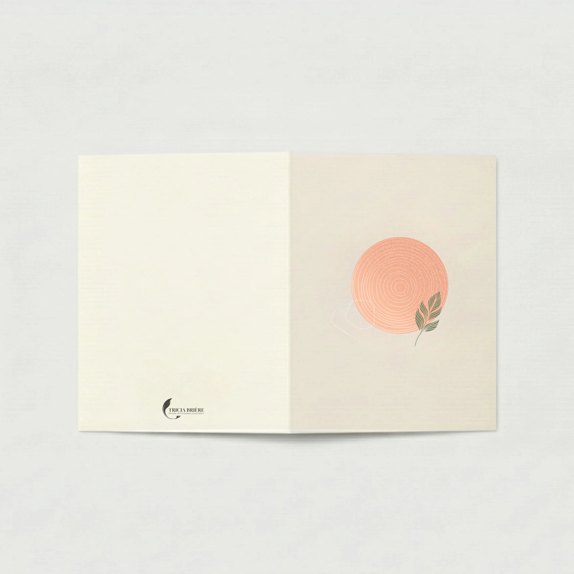 Carte de vœux ouverte à plat sur fond gris clair. La page de gauche est ivoire uni avec le logo Tricia Brière en bas à gauche. La page de droite, en beige rosé, est ornée d'un cercle rose poudré aux cernes concentriques blancs et d'une feuille verte stylisée.