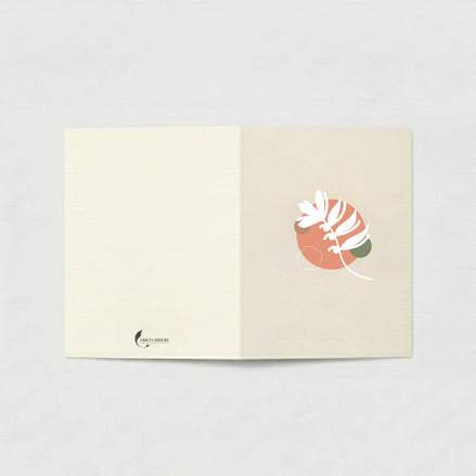 Carte de vœux ouverte à plat sur fond gris clair. La page de gauche est ivoire uni avec le logo Tricia Brière en bas à gauche. La page de droite, en beige rosé, présente une illustration botanique abstraite : un cercle terracotta avec des formes végétales blanches stylisées et un accent vert sauge.