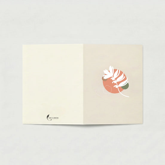 Carte de vœux ouverte à plat sur fond gris clair. La page de gauche est ivoire uni avec le logo Tricia Brière en bas à gauche. La page de droite, en beige rosé, présente une illustration botanique abstraite : un cercle terracotta avec des formes végétales blanches stylisées et un accent vert sauge.