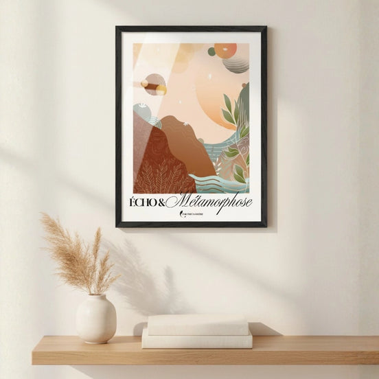 Affiche artistique « Écho & Métamorphose » par Tricia Brière, encadrée en noir, suspendue au-dessus d'une étagère en bois avec un vase blanc et des herbes de la pampa séchées.