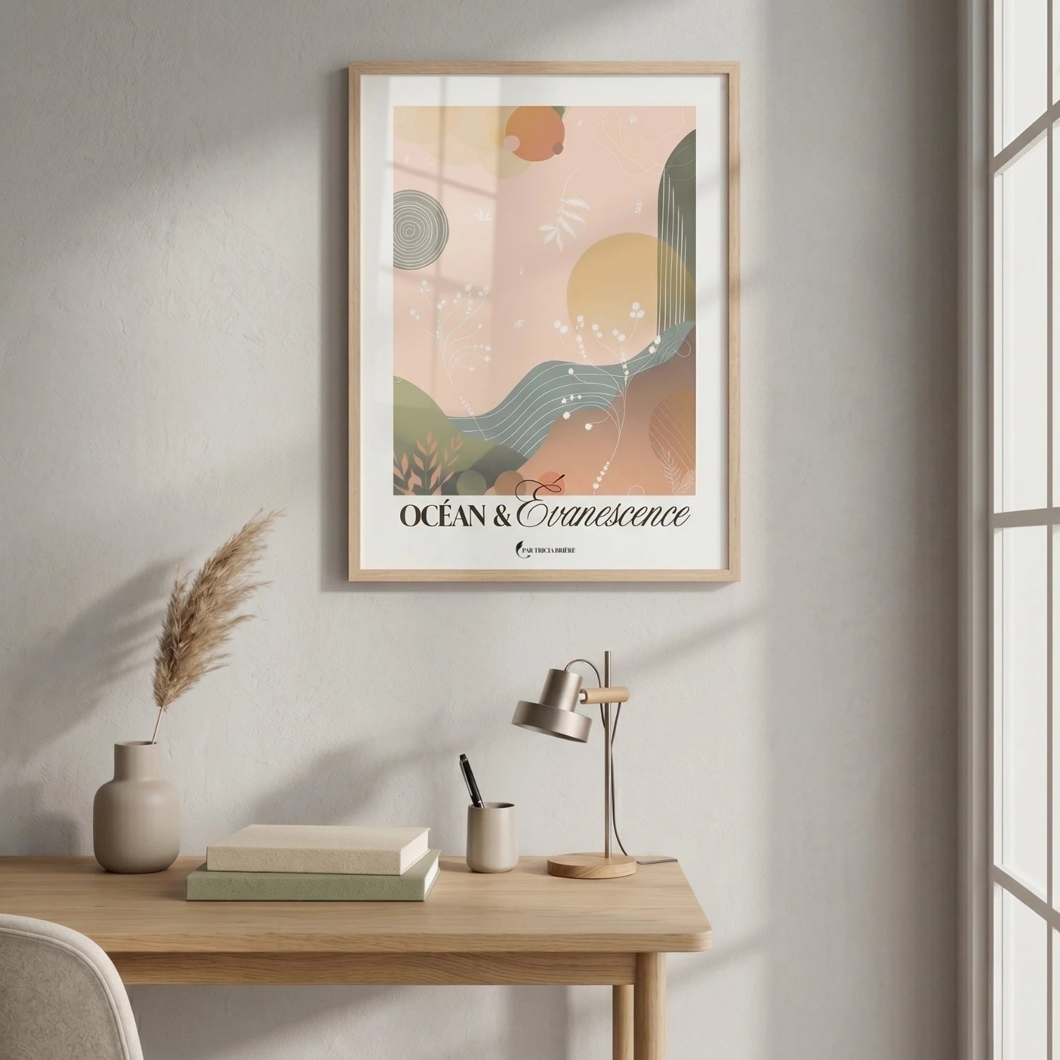Affiche « Océan & Évanescence » de Tricia Brière encadrée en bois naturel, accrochée au-dessus d'un bureau en chêne clair avec une lampe argentée, un pot à crayons et une herbe de la pampa dans un vase beige.