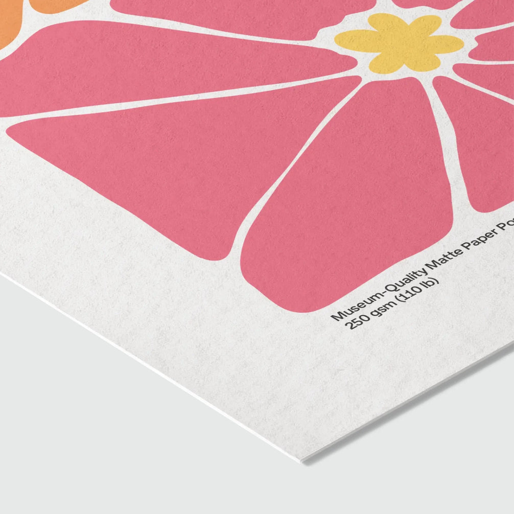 Gros plan sur le coin d'une impression sur papier mat qualité muséale 250 gsm (110 lb), montrant la texture légèrement granuleuse du support. Impression florale rose et jaune en arrière-plan.